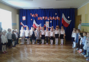 Dzieci śpiewają Mazurek Dąbrowskiego w postawie na baczność